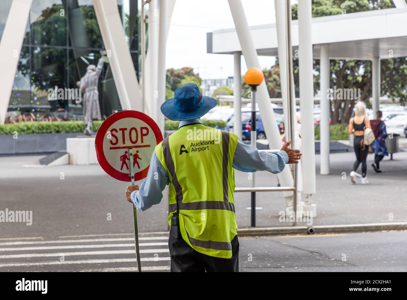 Auckland, New Zealand: Crossing guard with Stop sign at a zebra crossing in front of the terminal of Auckland International Airport Stock Photo