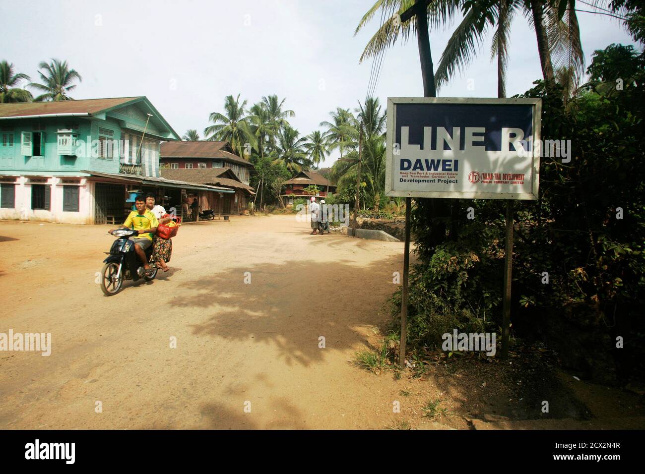 People on a moped drive past a sign indicating the economic zone near Dawei  in southern Myanmar, near the site of a planned special economic zone and  deep sea port, November 19,