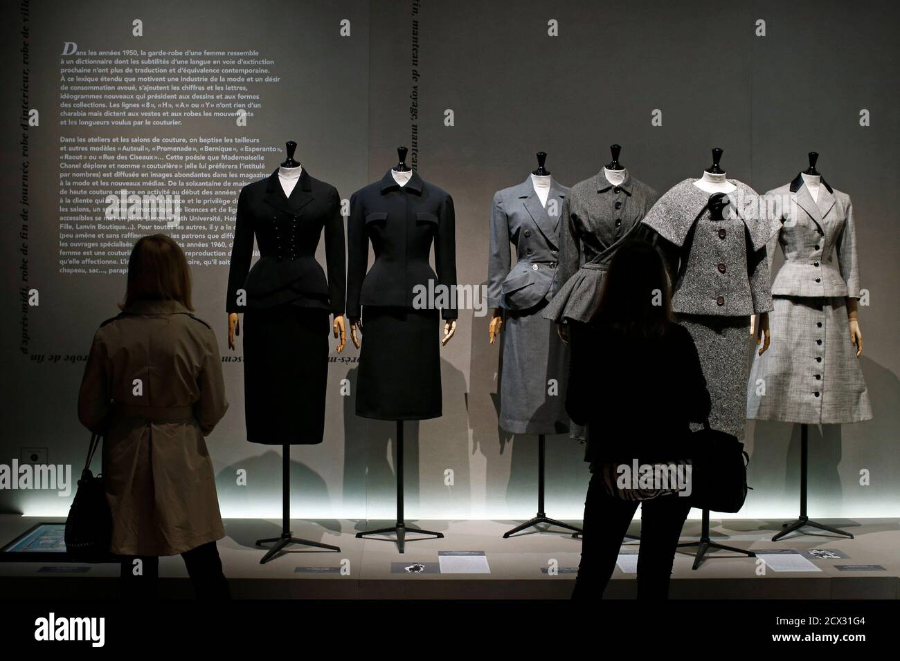 Visitors look at vintage dresses by designers Balenciaga, Christian Dior,  Pierre Cardin and Jacques Fath presented in the exhibition 