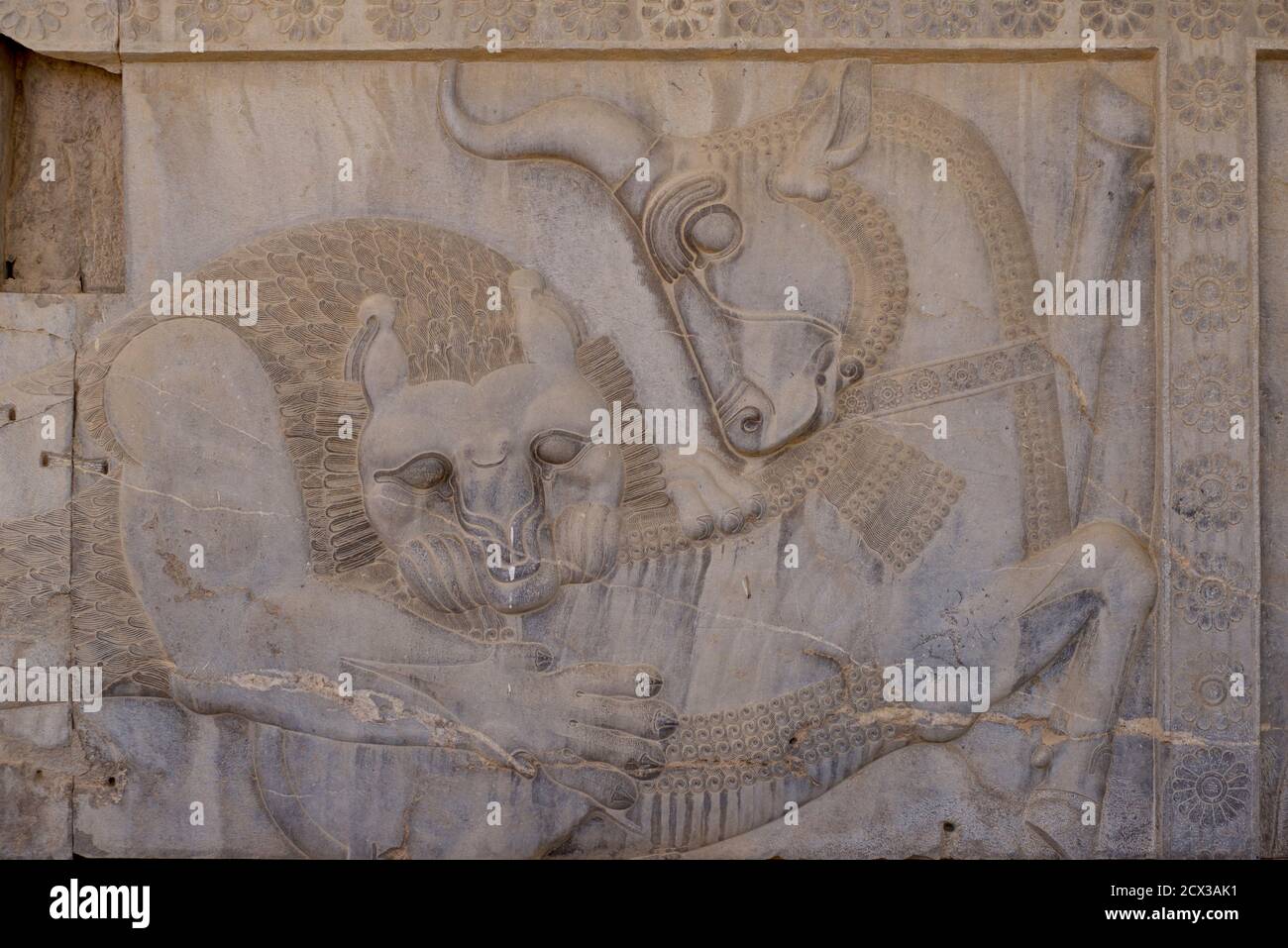 Apadana palace ruins and bas reliefs, Persepolis, Iran. Lion biting the bull. Relief depicting the symbolic coming of spring and the Nowruz festivity, through lion (sun) feasting on the bull (earth); Persepolis, Iran. Symbols of submission Stock Photo