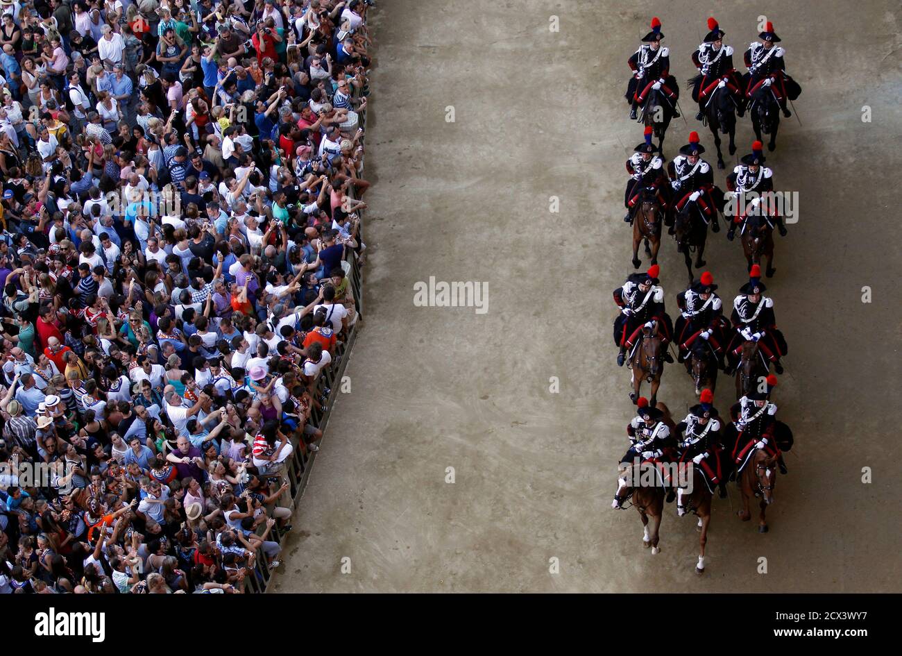Italian Carabinieri police arrive during their parade prior to a training session of the Palio race in Siena's main square August 15, 2012. Every year on August 16, almost without fail since the mid-1600s, 10 riders compete bareback around Siena's shell-shaped central square in a bid to win the Palio, a silk banner depicting the Madonna and child. REUTERS/Alessandro Bianchi (ITALY - Tags: SOCIETY ANIMALS SPORT HORSE RACING) Stock Photo