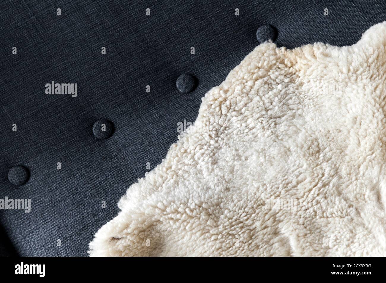Natural white sheepskin covers dark gray sofa, background photo texture Stock Photo
