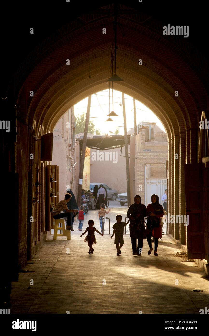 Moody late afternoon light penetrates the bazaar area, Yazd, Iran. Silhouetted Iranian family. Stock Photo