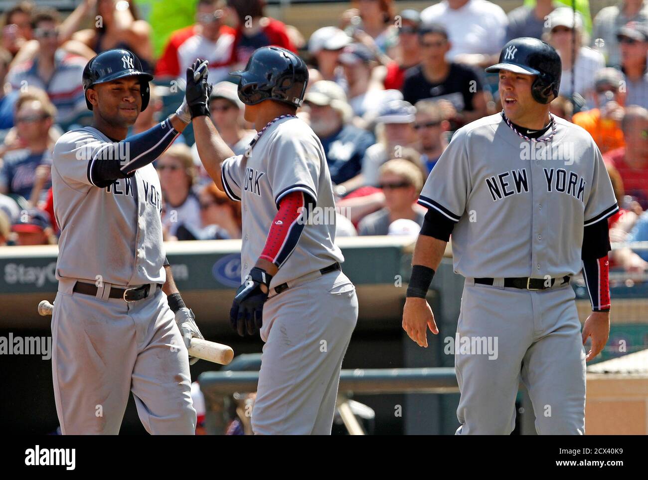 New York Yankees on-deck batter Zoilo Almonte (L) celebrates with teammates Alberto Gonzalez (C) and Austin Romine (R) who score on a hit by Yankees Ichiro Suzuki off Minnesota Twins pitcher Brian Duensing during the sixth inning of their American League MLB baseball game in Minneapolis, July 4, 2013.   REUTERS/Eric Miller (UNITED STATES - Tags: SPORT BASEBALL) Stock Photo