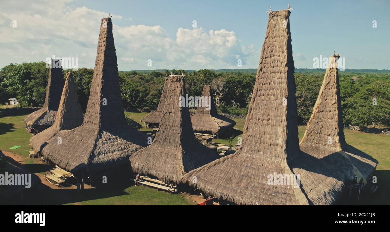 Aerial closeup view of traditional village with ornately roofs cottages. Tropical forest at long-held tradition countryside settlement. Indonesia landscape of Sumba Island attraction in drone shot Stock Photo