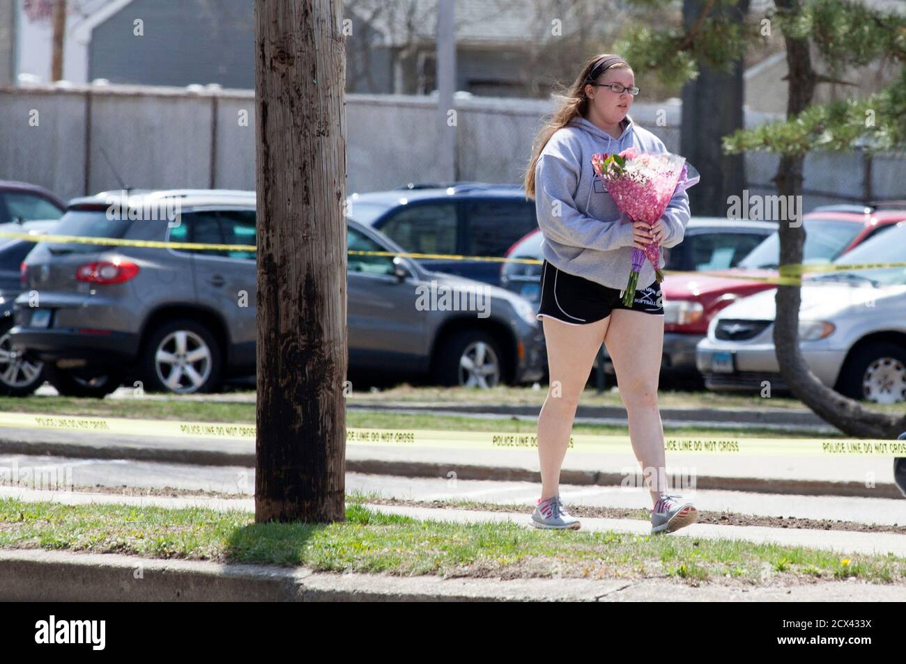 A girl walks with flowers in front of Jonathan Law High School in Milford, Connecticut April 25, 2014. A 16-year-old girl was killed on Friday in an attack inside a Connecticut high school and authorities were investigating reports she was stabbed by a fellow student after rejecting his invitation to the prom, police said. The victim, Maren Sanchez, a junior at Jonathan Law High School in Milford, was pronounced dead at the hospital shortly after the 7 a.m. (1100 GMT) attack, Milford Police Chief Keith Mello told a news conference. REUTERS/Michelle McLoughlin (UNITED STATES - Tags: EDUCATION C Stock Photo