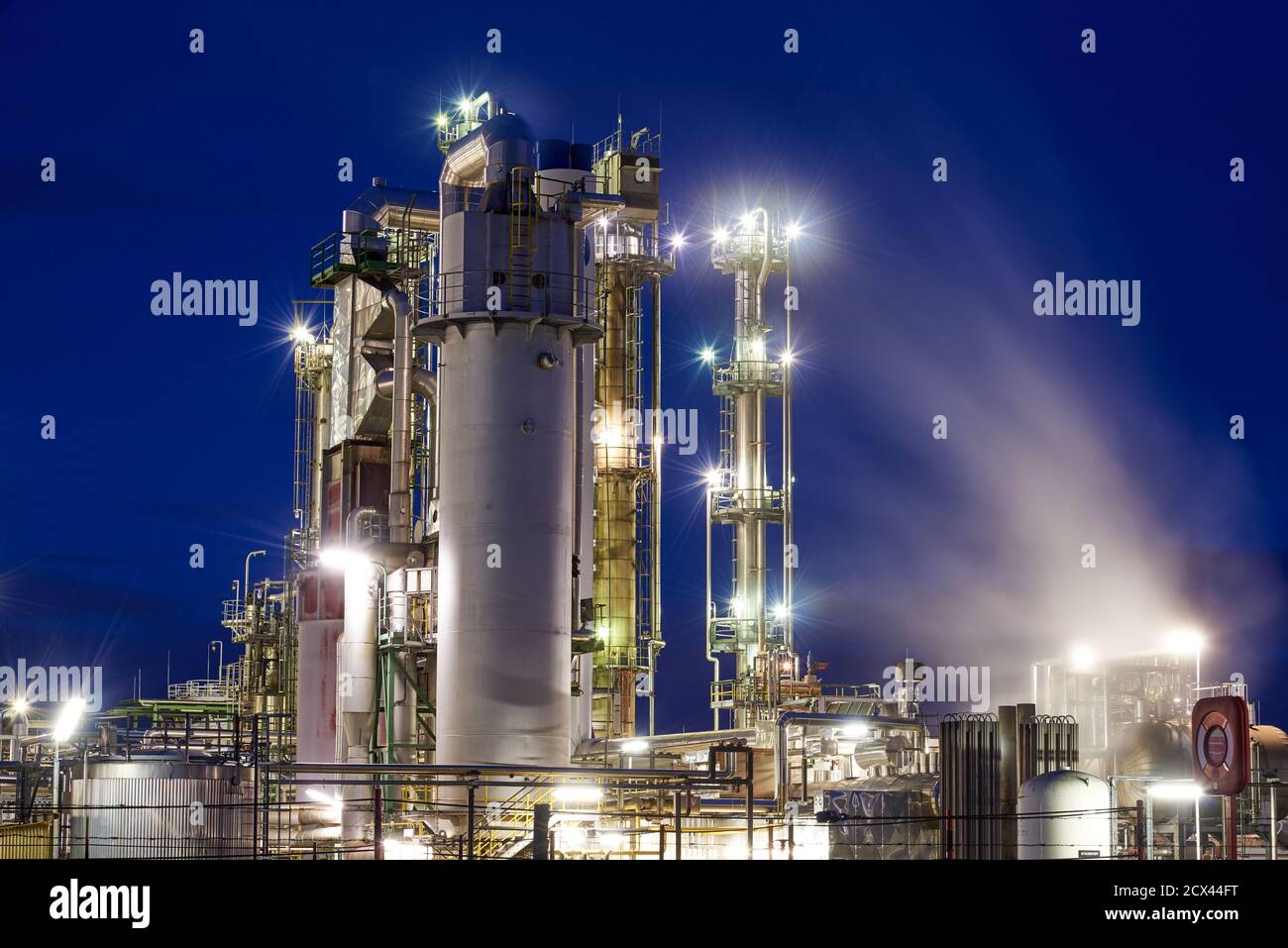 Oil refinery after sunset with lights and steam Stock Photo - Alamy