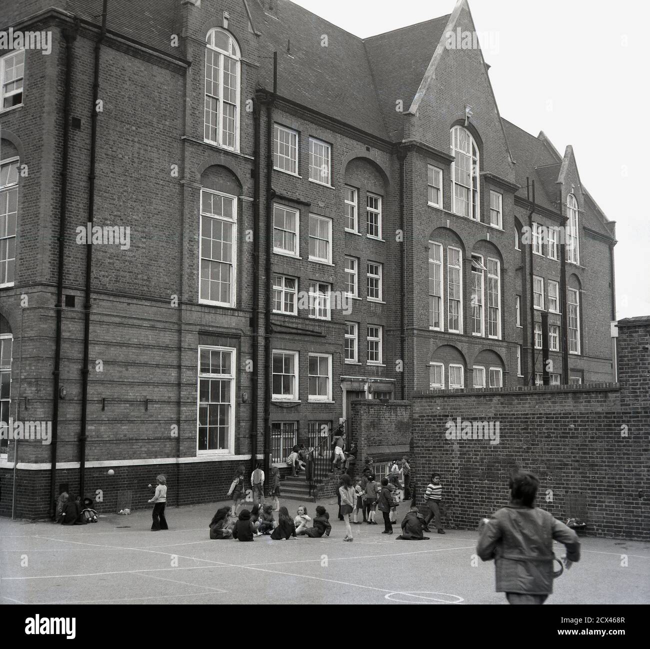 1960s, historical, children in a playground outside a large inner London primary school, South-east London, England, UK, a tradittional school building from the Victorian era. Stock Photo