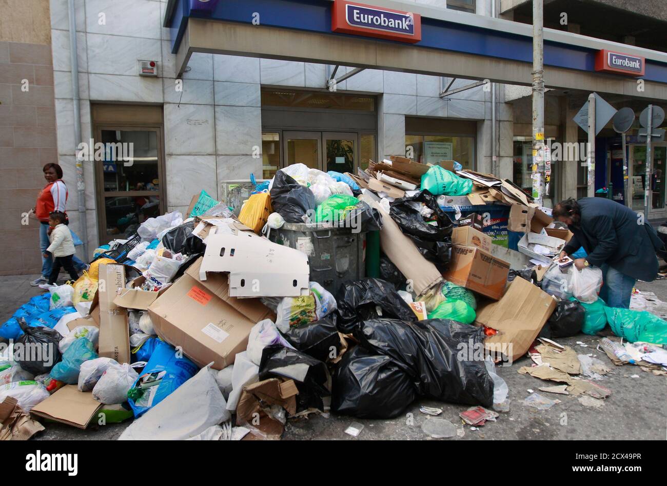 A man searches in a pile of garbage in front of a bank branch in Athens,  October 12, 2011. Municipal workers, who oppose planned wage cuts, have  blocked the entrances to garbage