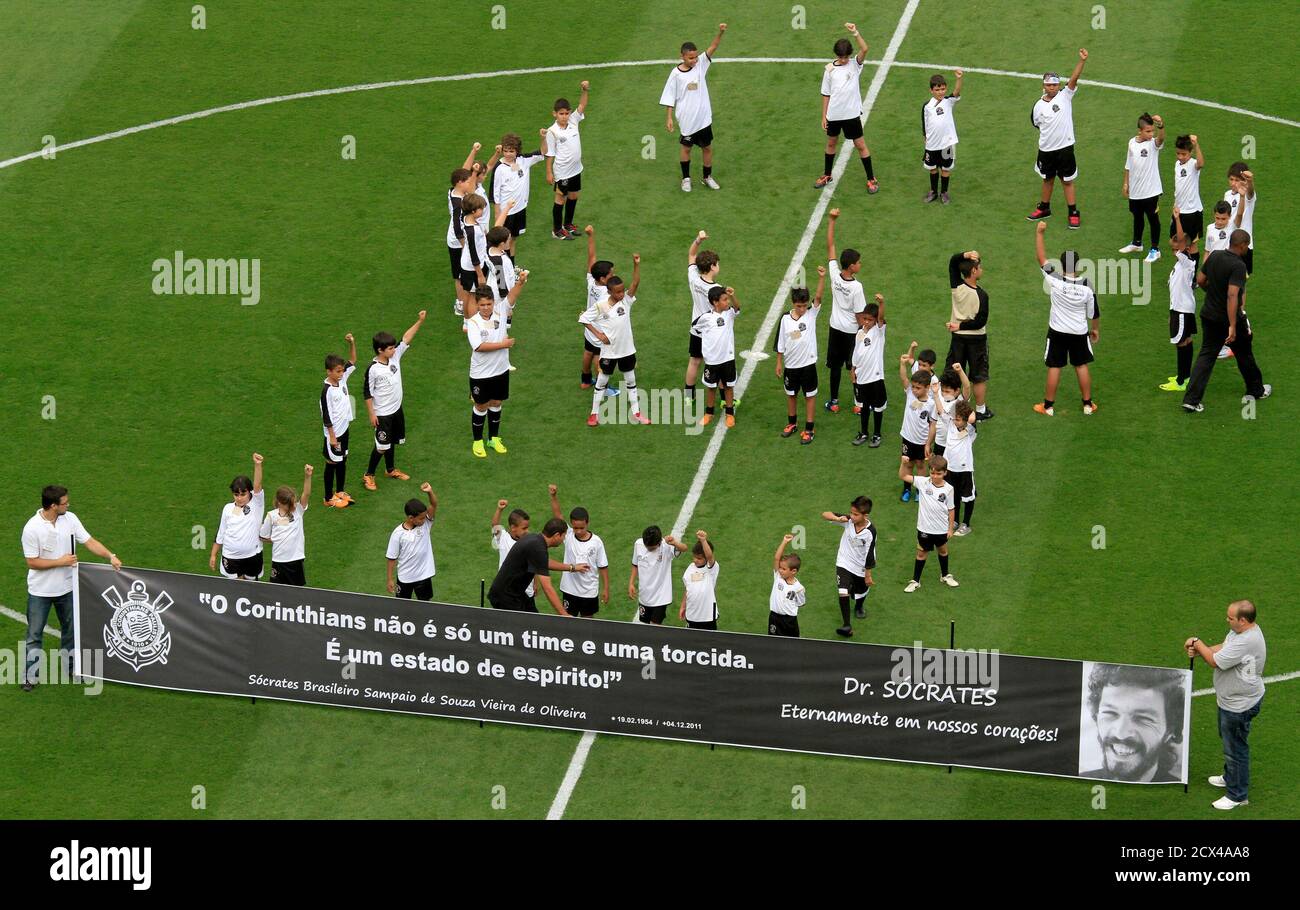 A banner with the picture of Brazil former soccer player Socrates is seen on the pitch next to children before the Brazilian championship between Corinthians and Palmeiras in Sao Paulo December 4, 2011. Brazil 1982 World Cup captain Socrates, the 'Golden Heel' renowned as one of the great playmakers of his generation, died in hospital on Sunday of septic shock at the age of 57, his doctors said in a statement. The banner that reads " Socrates, Forever in our hearts ". REUTERS/Nacho Doce (BRAZIL - Tags: SPORT SOCCER OBITUARY) Stock Photo