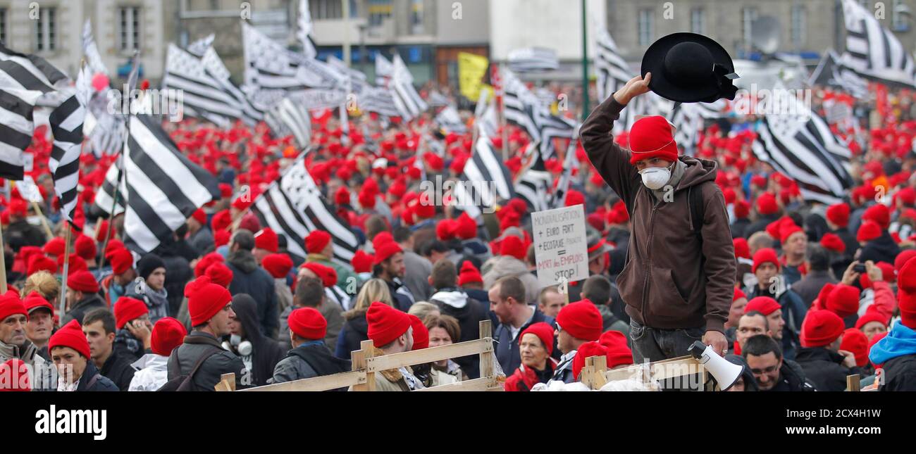A man waves a traditional black Breton hat as protesters with Brittany  regional flags and wearing red caps, the symbol of protest in Brittany,  take part in a demonstration to maintain jobs