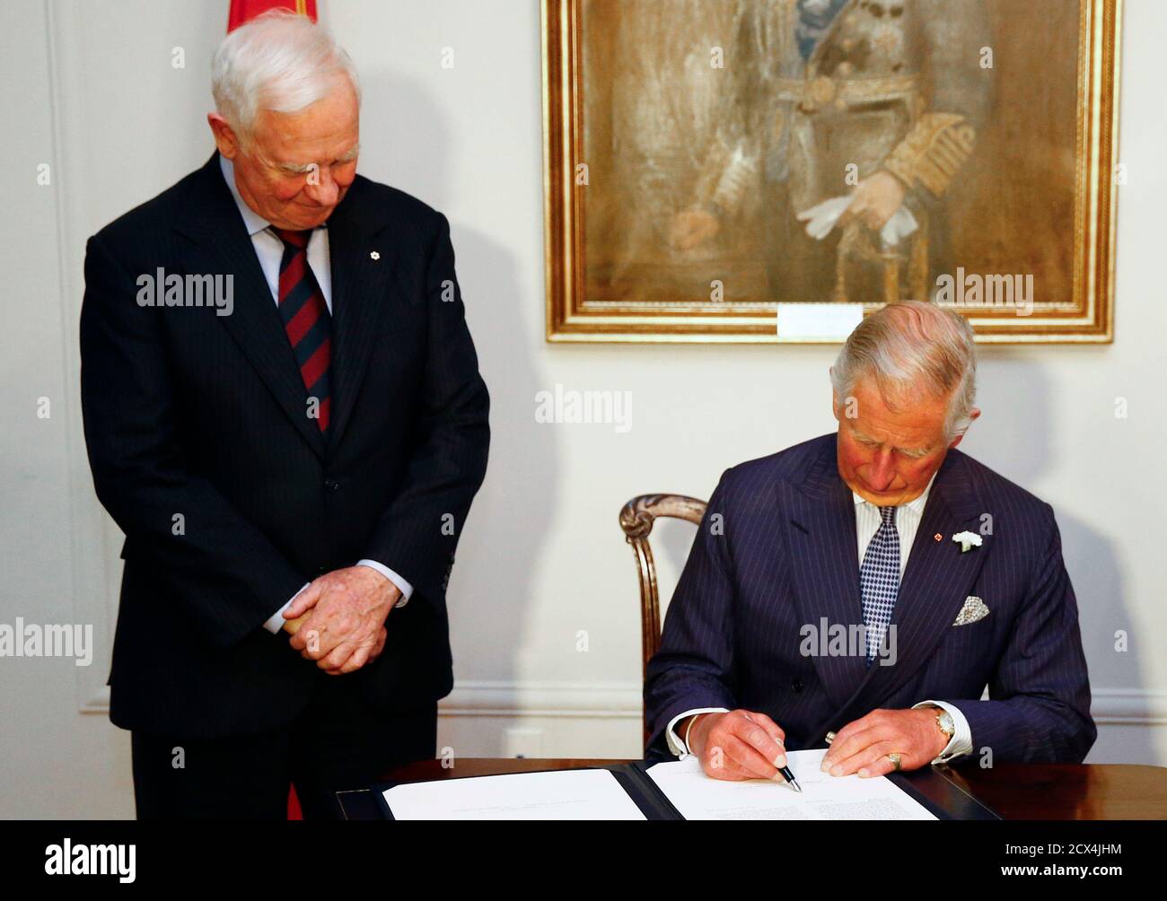 Britain's Prince Charles signs a document to be sworn in as a member of the Canadian Privy Council beside Governor General of Canada David Johnson (L) in Halifax, Nova Scotia May 18, 2014. The royal couple are on a four-day visit to Canada that begins in Halifax and includes stops in Pictou, Nova Scotia, the Prince Edward Island towns of Charlottetown, Bonshaw and Cornwall and concludes in Winnipeg.   REUTERS/Mark Blinch (CANADA - Tags: ROYALS SOCIETY ENTERTAINMENT) Stock Photo