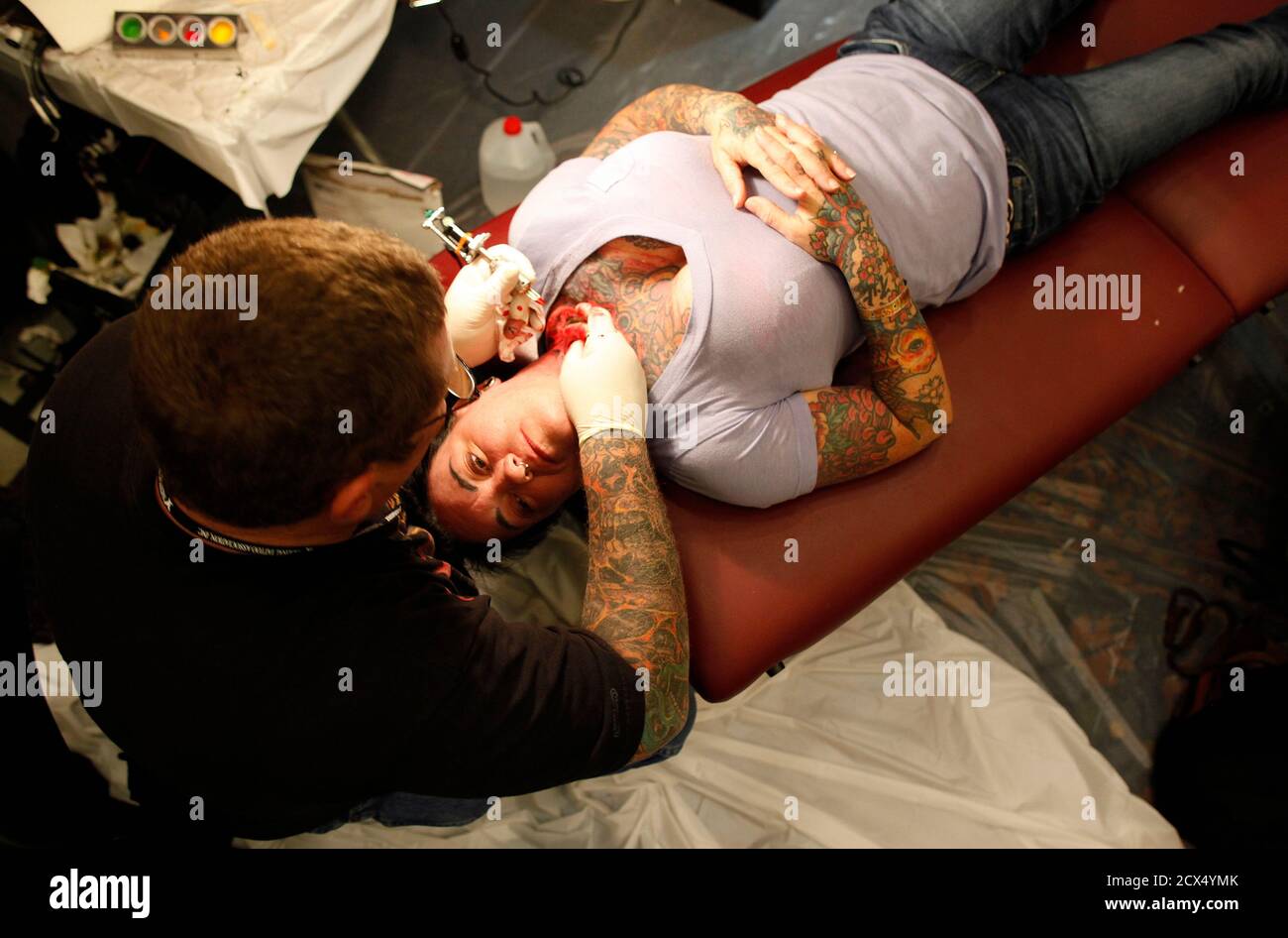 A woman has her neck tattooed during the National Tattoo Association  Convention in Cincinnati, Ohio, April 14, 2012. The hobby of collecting  tattoos has exploded into the mainstream in society with tattoo