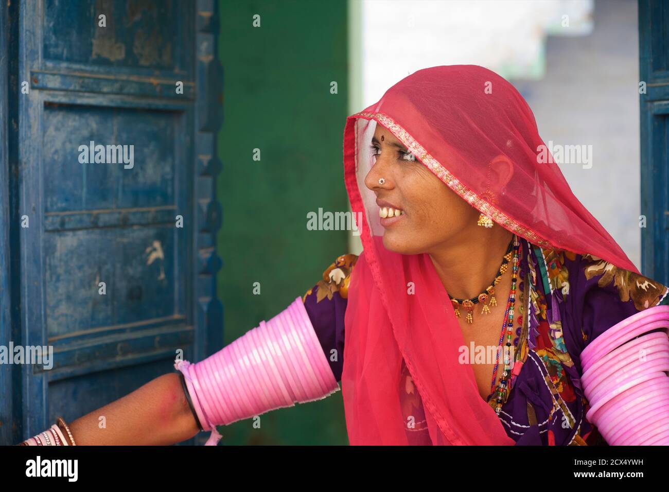 Rajasthani woman in colourful sari at the door to her village home ...