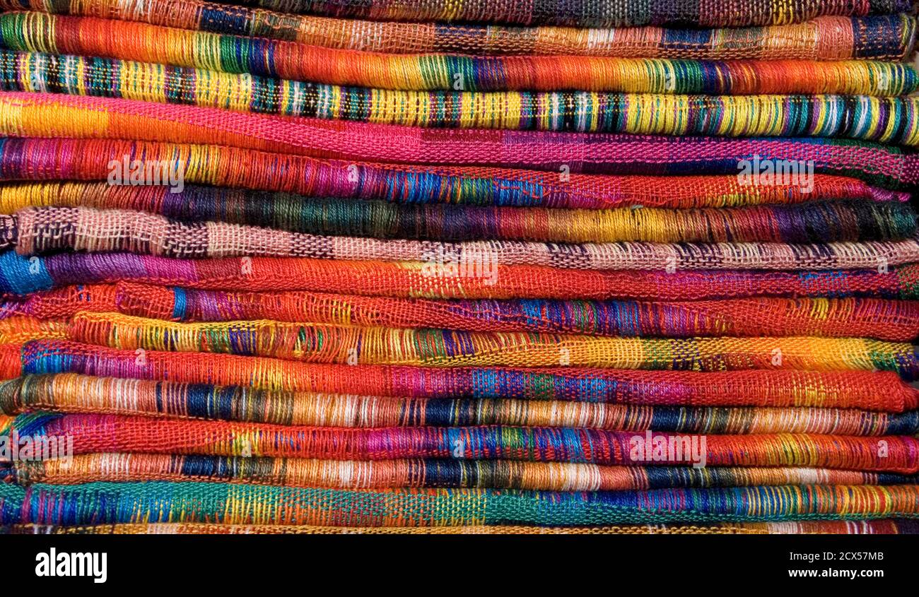 A stack of brightly coloured fabrics for sale on a market stall in Panajachel.  As sold on market stalls in Antigua, Chichicastenango, Panajachel and other popular tourist spots in Guatemala Stock Photo