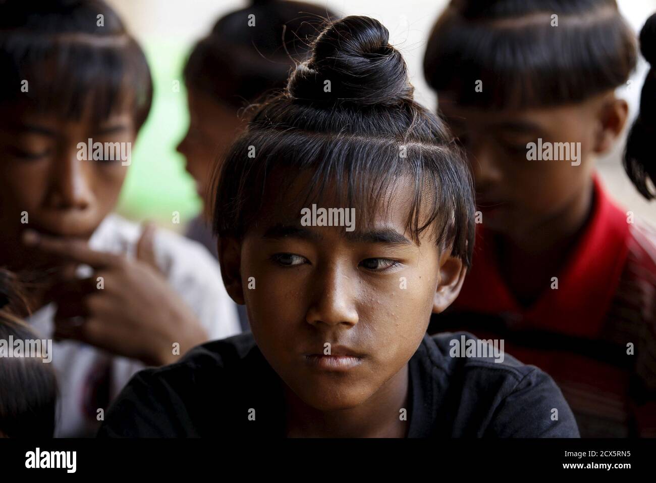 Zaw Myo Aung (C), 13, sits with others boys who all sport the ancient  hairstyle known as Sanyitwine in a monastery at Sat Sat Yo village in  Nyaung Oo township, near Myanmar's