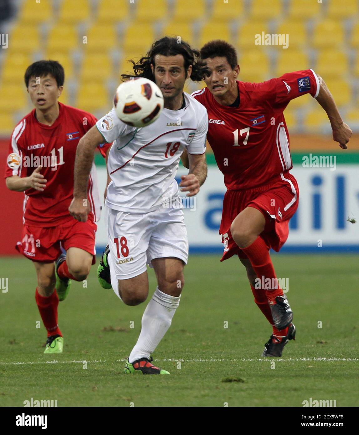 Iran's Pejman Nouri (C) fights for the ball with North ...