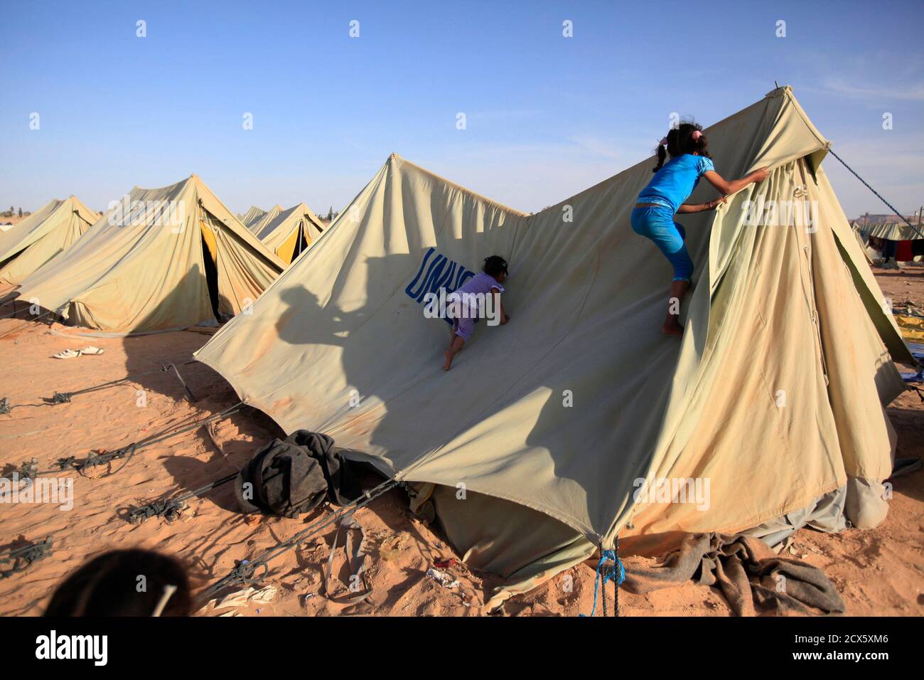 Libyan refugees who fled unrest in Libya climb their tent at a refugee camp near the southern Libyan and Tunisian border crossing of Dehiba May 8, 2011. REUTERS/Zohra Bensemra (TUNISIA - Tags: POLITICS CIVIL UNREST IMAGES OF THE DAY CONFLICT SOCIETY) Stock Photo