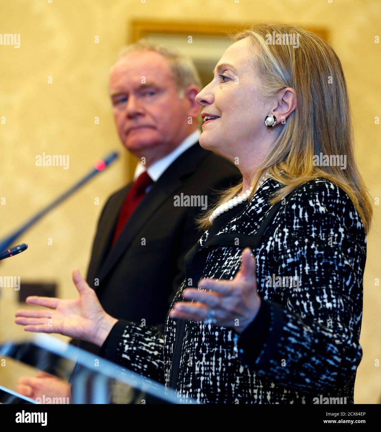 U.S. Secretary of  State Hillary Clinton speaks during a news conference as Northern Ireland's Deputy First Minister Martin McGuinness listens at Stormont Castle in Belfast December 7, 2012. Clinton travelled to Northern Ireland on Friday to lend her support to the British province's fragile peace, the frailty of which was underlined by overnight rioting on the eve of her visit and the seizure of a bomb. REUTERS/Kevin Lamarque (NORTHERN IRELAND - Tags: POLITICS) Stock Photo