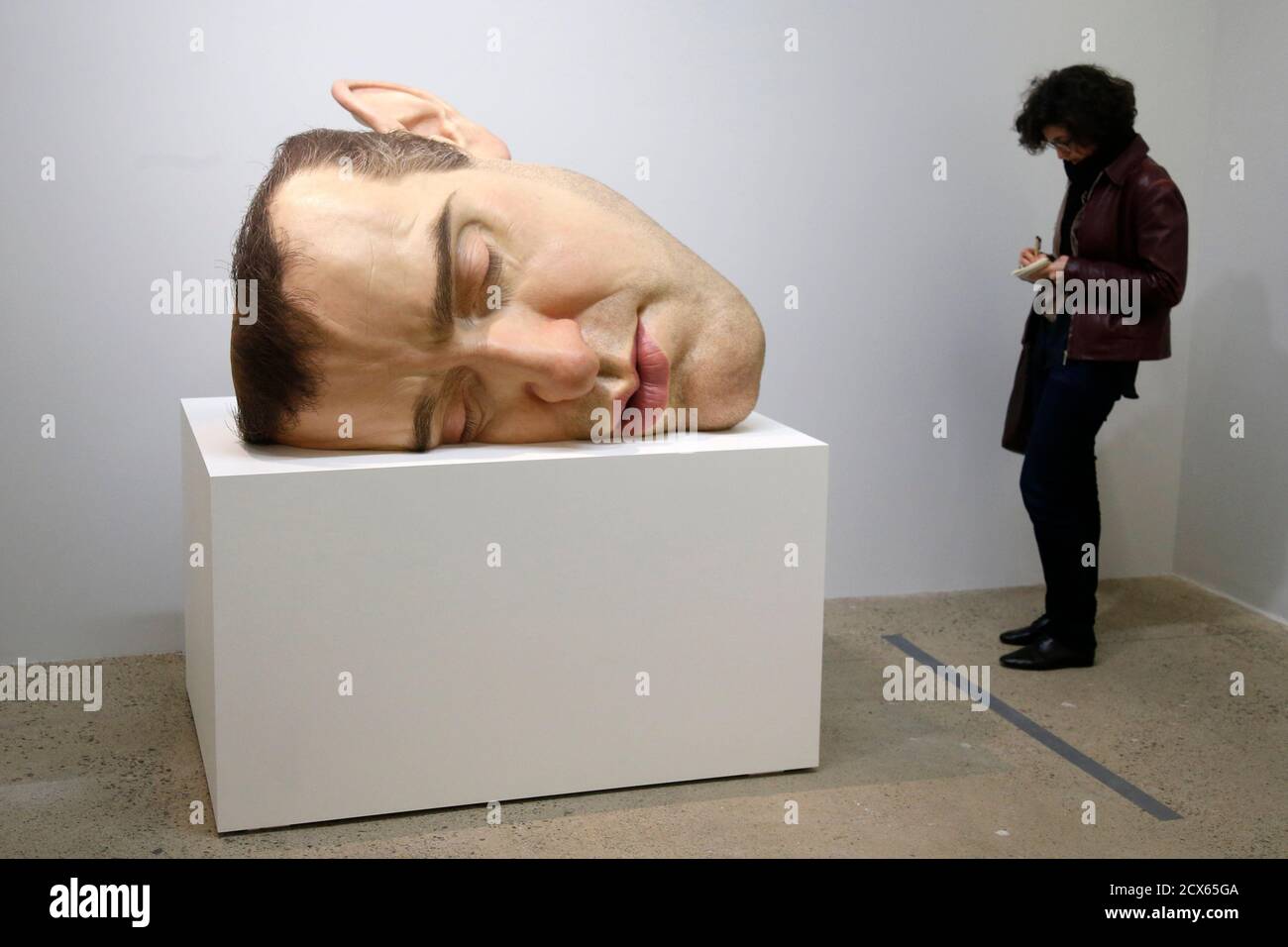 A visitor looks at a sculpture entitled "Mask II" (2002) by artist Ron Mueck during the press day his exhibition at the Fondation pour l'art contemporain in Paris April 15,