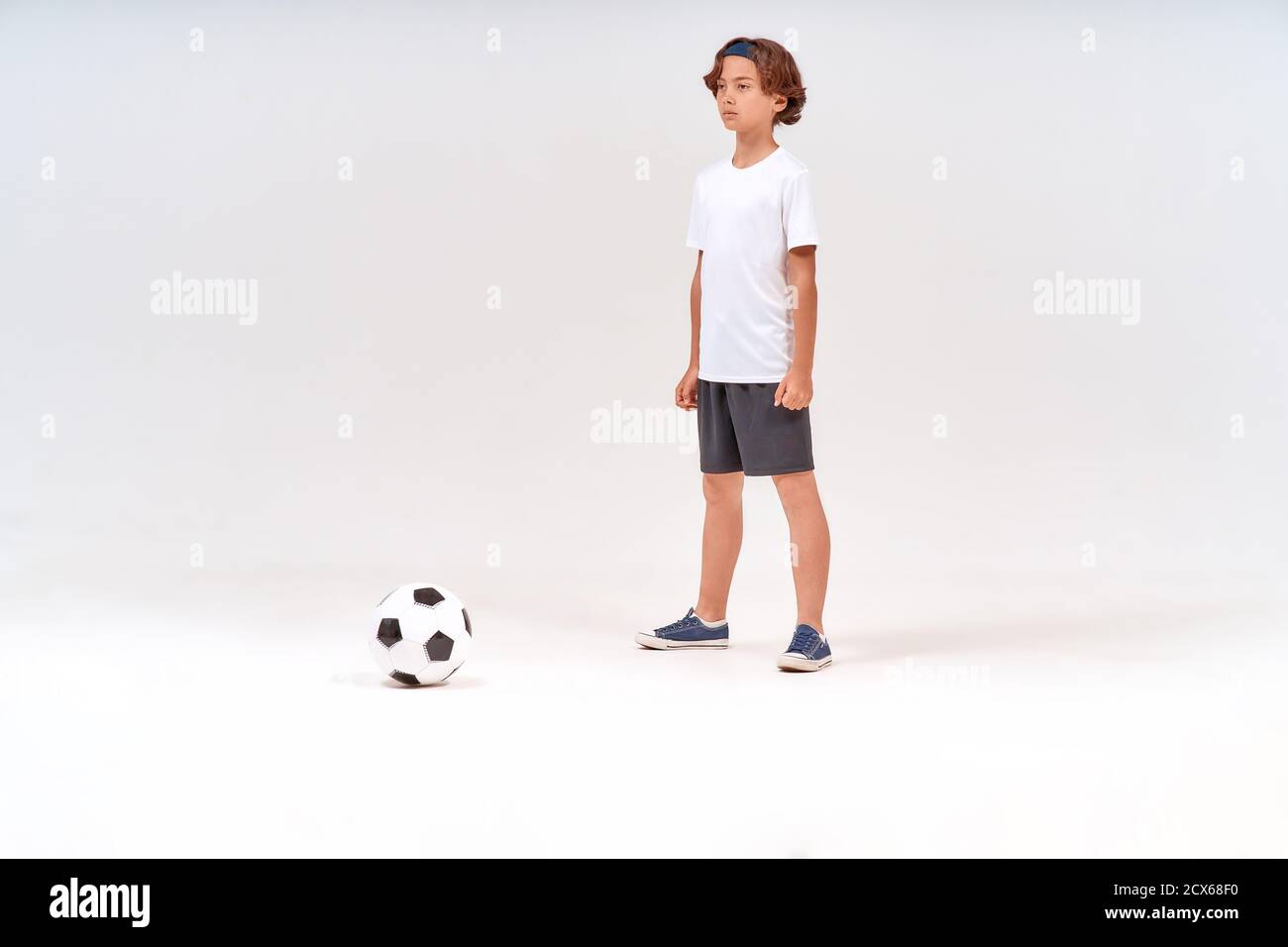 Young soccer player. Full-length shot of a teenage boy playing away while playing football isolated over grey background Stock Photo