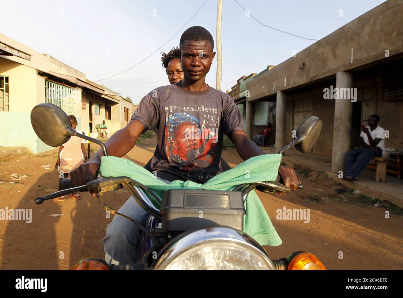 A motorcyclist taxi-driver wearing a T-shirt with the image of U.S.  President Barack Obama carries a passenger at the trading centre in the  village of Kogelo, west of Kenya's capital Nairobi, July