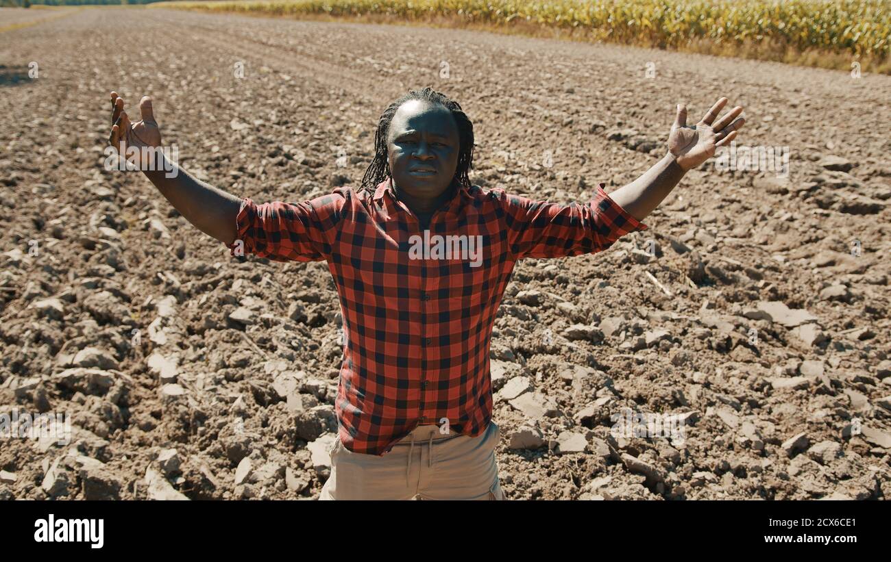 Happy african man, farmer looking around the plowed farmland with ...