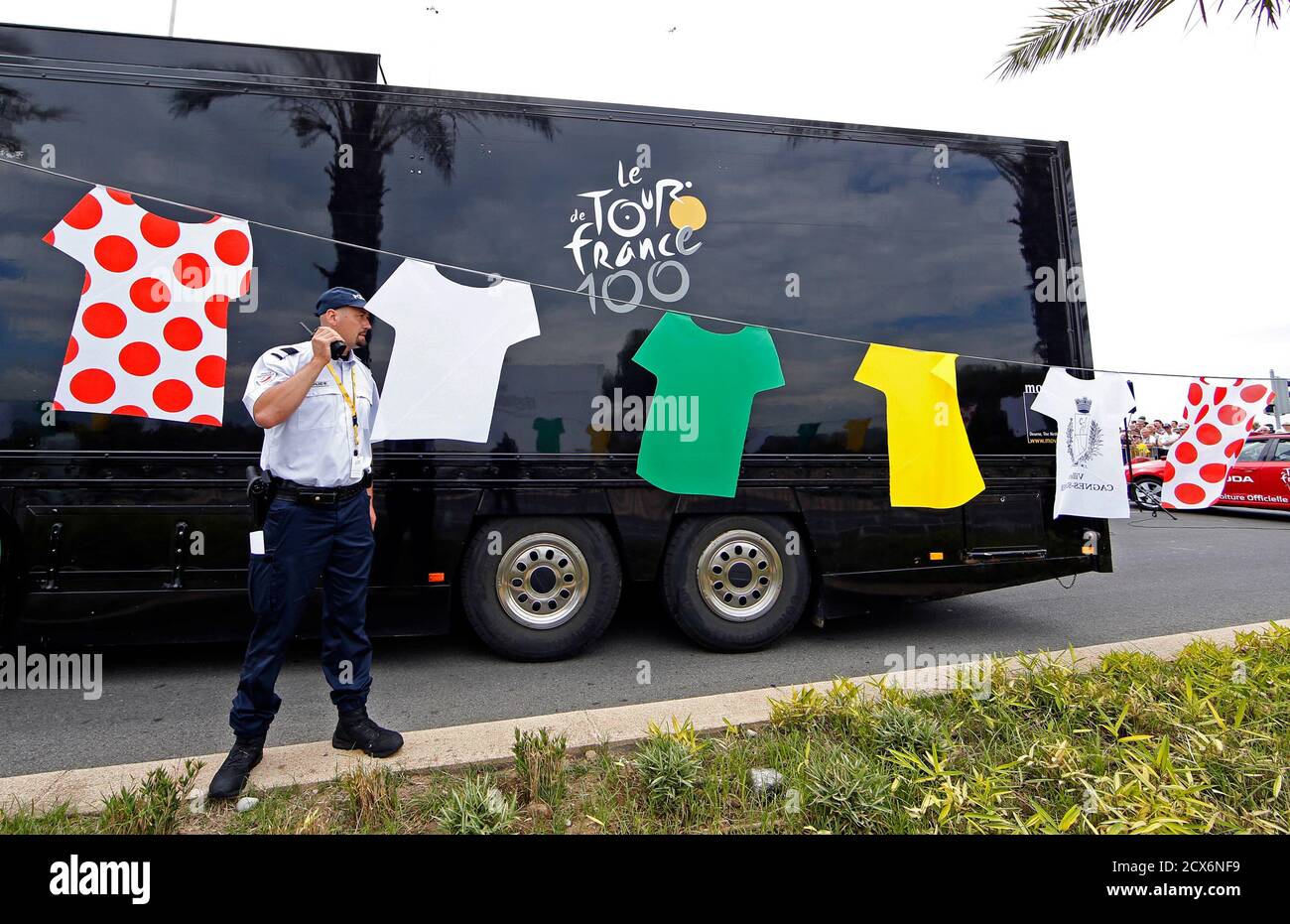 A policeman stands in front of a truck near cycling jersey which hang from  a line at the departure of the 228.5 km fifth stage of the centenary Tour  de France cycling