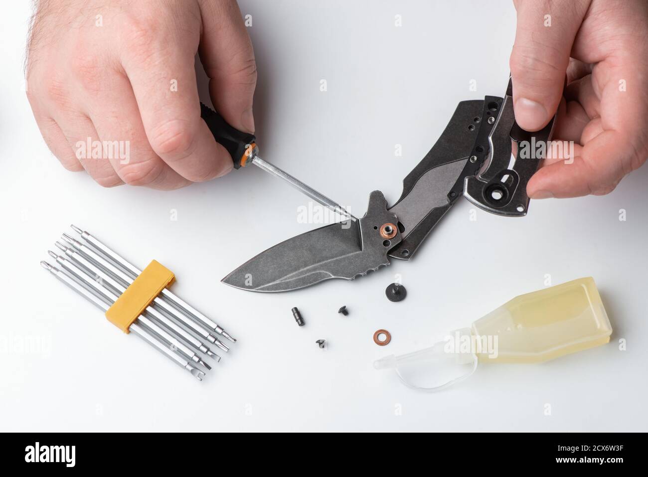 Repairman disassembling a folding knife with a screwdriver Stock Photo