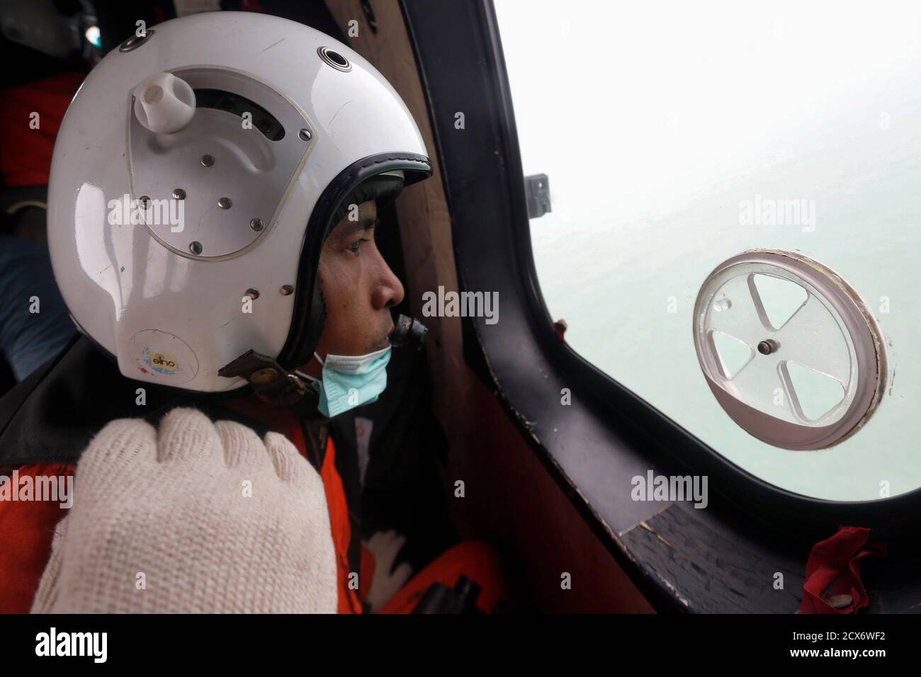 An Indonesian Air Force crew member looks out the windows of a Super Puma  helicopter during a search and rescue operation for AirAsia flight QZ8501,  over Kumai Bay, south of Pangkalan Bun,