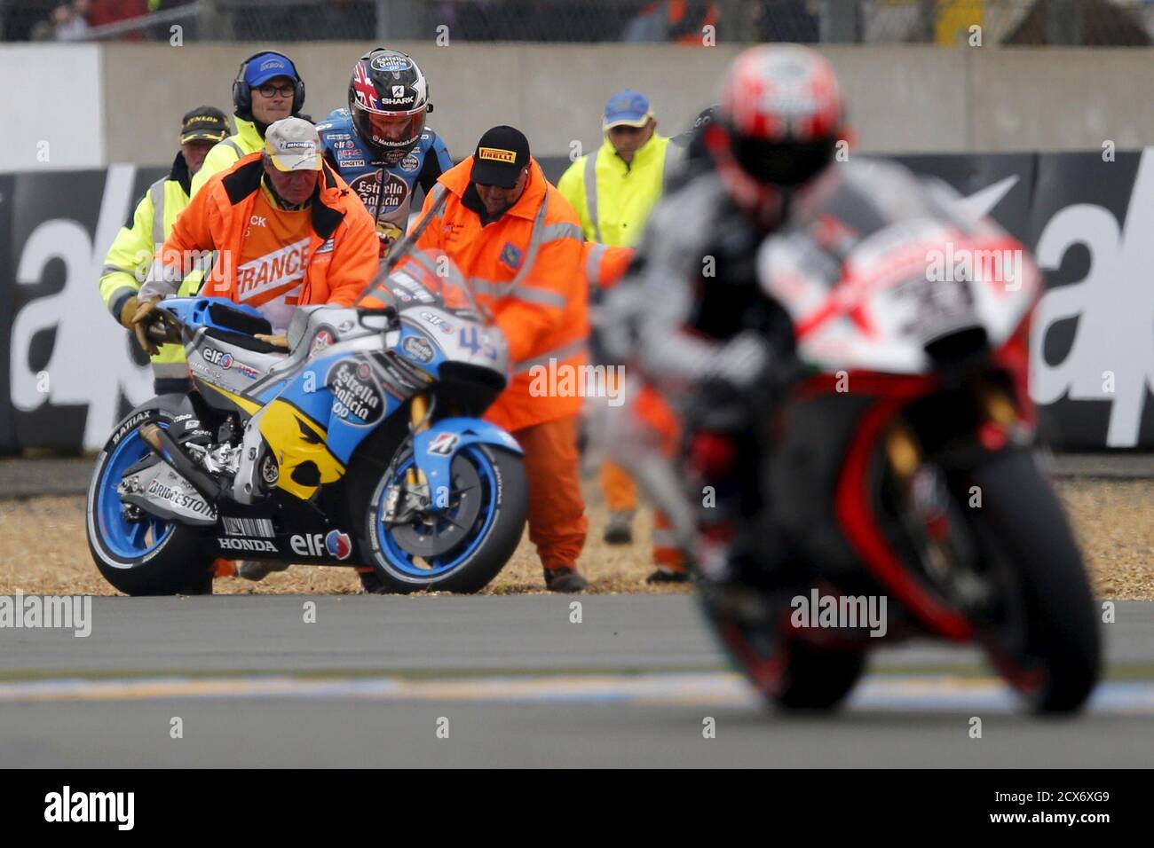 Track marshals push a motorcycle of Honda MotoGP rider Scott Redding of  Britain after he crashes during the qualifying session of the French Grand  Prix at the Le Mans circuit, in Le
