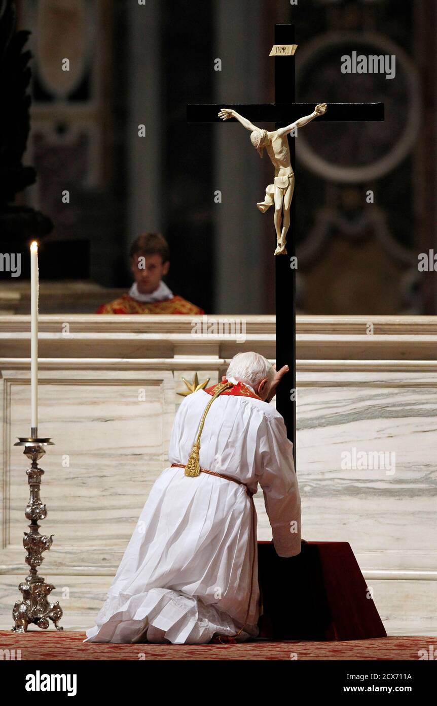 Pope Benedict XVI kneels in front of a cross as he leads the Passion mass  at Saint Peter's Basilica at the Vatican April 22, 2011. REUTERS/Alessandro  Bianchi (ITALY - Tags: RELIGION Stock