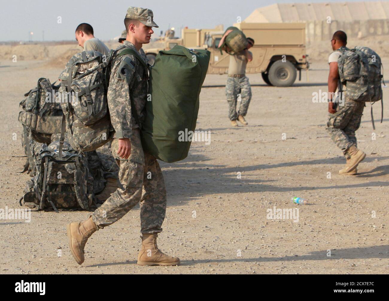 U.S. soldiers from the 1st Battalion, 116th Infantry Regiment, carry their luggage as they prepare to pull out from Iraq to Kuwait, at Tallil Air Base near Nassiriya, 300 km (185 miles) southeast of Baghdad, August 15, 2010. Picture taken August 15, 2010.  REUTERS/Thaier al-Sudani (IRAQ - Tags: CONFLICT SOCIETY) POLITICS MILITARY) Stock Photo