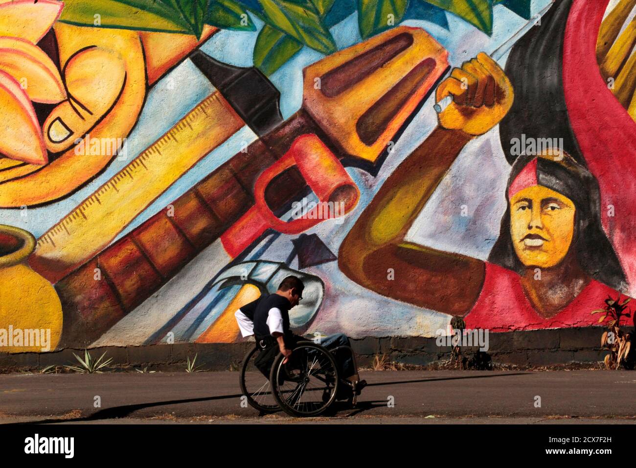 A disabled man passes in front of a mural depicting the workers and peasants revolution, in Managua January 14, 2011. REUTERS/Oswaldo Rivas (NICARAGUA - Tags: SOCIETY) Stock Photo