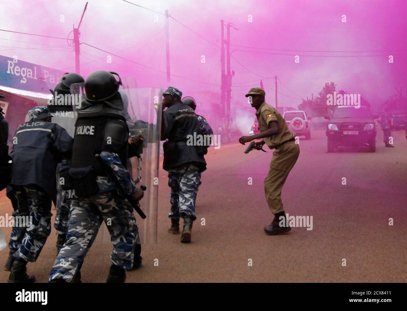 Riot policemen run through a cloud of coloured teargas to disperse  supporters of Uganda's opposition marching on a street in Masaka town, 120  km (72 miles) southwest of the capital Kampala August