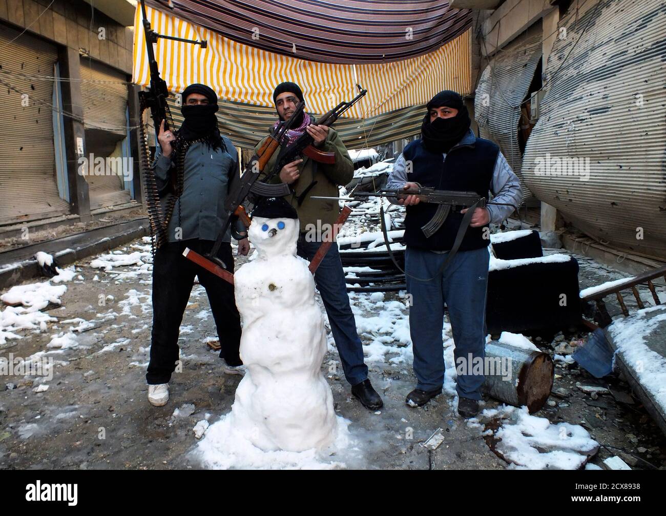 Members of the Free Syrian Army pose with their weapons and a snowman at the Jouret al Shayah area in Homs January 10, 2013. Picture taken January 10, 2013.                            REUTERS/Yazan Homsy (SYRIAS - Tags: CONFLICT MILITARY TPX IMAGES OF THE DAY) Stock Photo