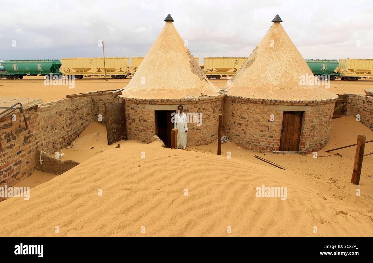 A worker stands near buildings surrounded by sand as a result of desert encroachment near the Ogrein Railway Station at the Red Sea State August 1, 2013. REUTERS/Mohamed Nureldin Abdallah (SUDAN - Tags: ENVIRONMENT SOCIETY) Stock Photo