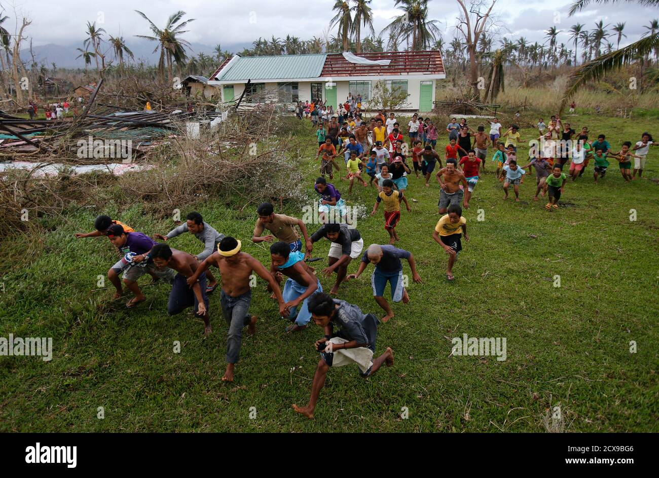 Survivors of the Super Typhoon Haiyan run to receive aid being deployed by  helicopter by the Philippine Air Force to a mountainous area inaccessible  by vehicles west of Tacloban city, in the