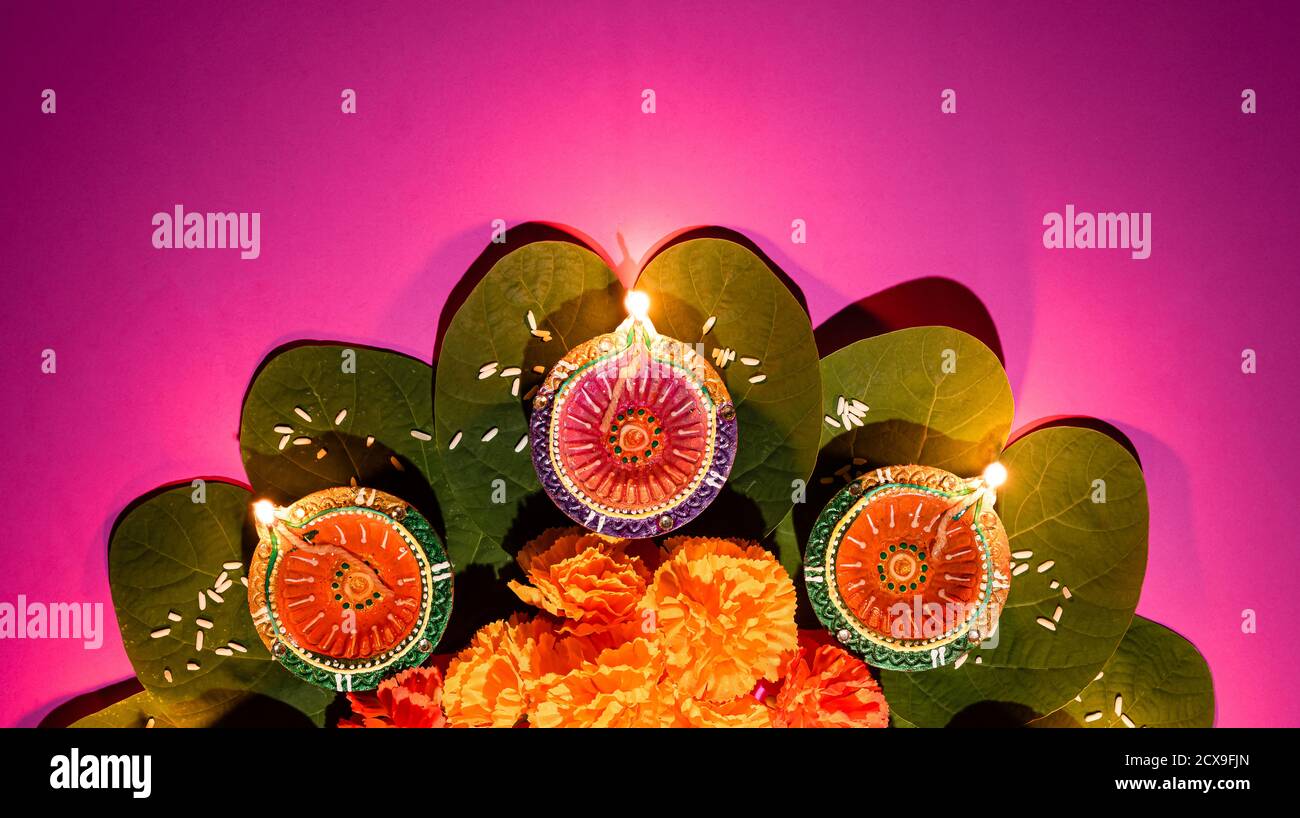 Happy Dussehra. Clay Diya lamps lit during Dussehra with yellow flowers, green leaf and rice. Dussehra Indian Festival concept. Stock Photo