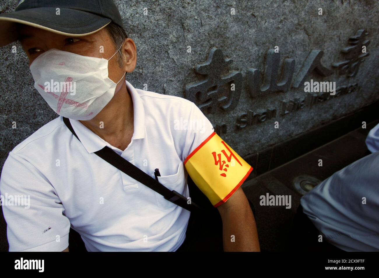 An employee wears a mask during a protest against Nan Shan Life, which is the Taiwan unit of AIG, outside their building headquarters in Taipei September 28, 2010. The protesters claim that the company is restricting employees' rights to freedom of speech by discouraging against the discussion of company matters with the media. AIG is sure of at least one bidder for its Taiwan Nan Shan Life unit should it put it back on the market, with Chinatrust Financial reaffirming its interest on September 21 after the original buyers pulled out. The words on the board read 'Cutting away the worker's unio Stock Photo