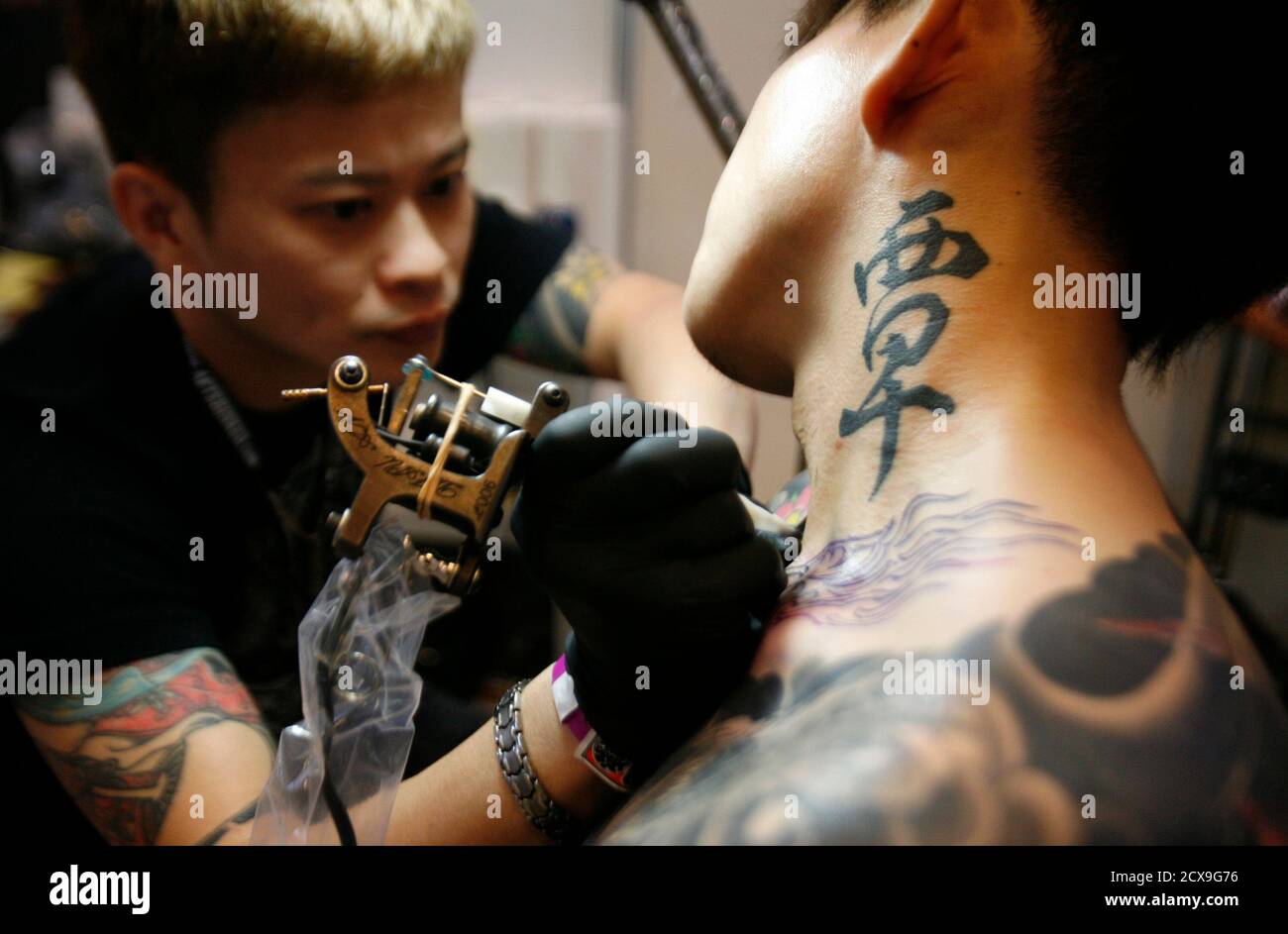 A tattoo artist works on a creation on the body of a festival-goer at the  Tattoo Art and Culture show in Singapore December 11, 2010. The event  brings together like-minded boutique inking