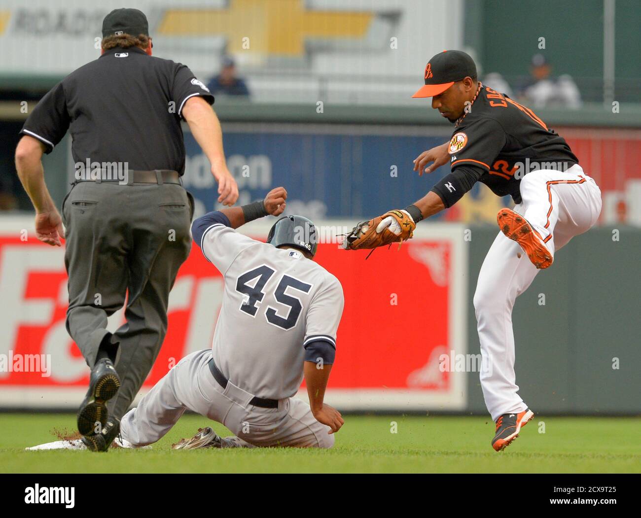 Baltimore Orioles second baseman Alexi Casilla can't get the tag down in time to catch New York Yankees baserunner Zoilo Almonte (C) on a stolen base during the second inning of their MLB American League baseball game in Baltimore, Maryland June 28, 2013.  REUTERS/Doug Kapustin (UNITED STATES - Tags: SPORT BASEBALL) Stock Photo