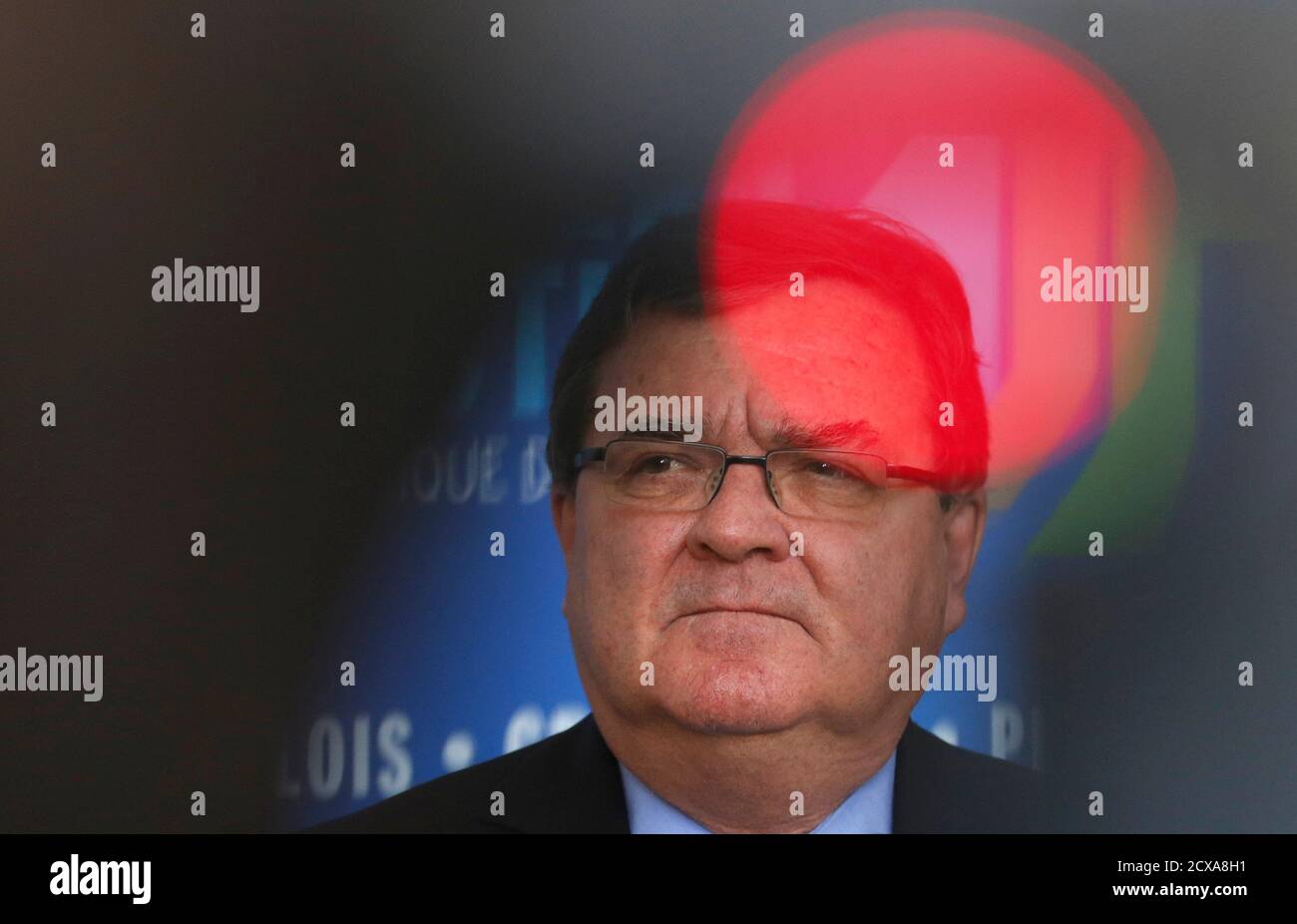 Canada's Finance Minister Jim Flaherty is framed between a cameraman and a television camera while listening to a question from a journalist after meeting with private sector economists in Ottawa March 8, 2013.  Private sector economists have cut their growth forecasts for the Canadian economy in 2013 due to volatile market conditions in the United States and Europe, Flaherty said on Friday. REUTERS/Chris Wattie (CANADA - Tags: POLITICS BUSINESS) Stock Photo