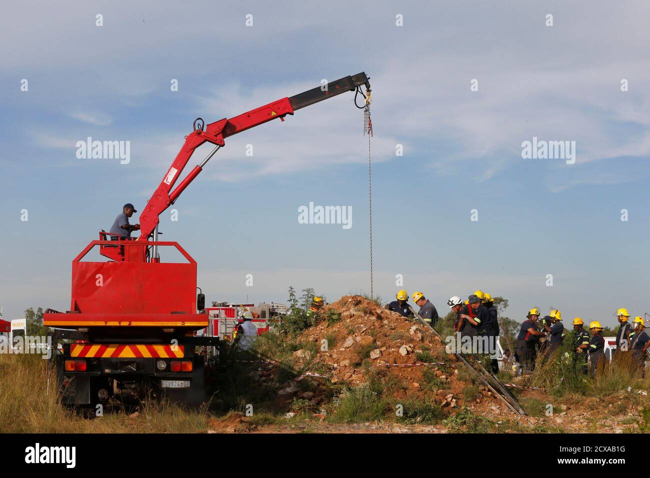 Rescue officials use a crane to remove debris as they work to rescue trapped suspected illegal miners from an abandoned gold shaft in Benoni, east of Johannesburg, February 16, 2014. South African rescuers started bringing to the surface at least 30 illegal miners on Sunday who had been trapped by debris in the abandoned gold shaft near Johannesburg, emergency services ER24 spokesman  Werner Vermaak said. There were no immediate reports of deaths or injuries. Vermaak later told Reuters that some of the miners still underground were refusing to come up, saying they did not want to be arrested.  Stock Photo