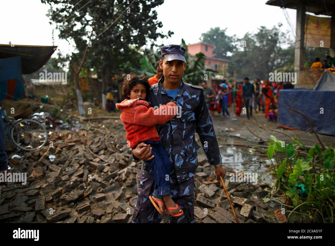 A police officer carries a girl to the lost and found camp after she got lost in the crowd during the 'Gadhimai Mela' festival held in Bariyapur November 29, 2014. Sword-wielding Hindu devotees in Nepal began slaughtering thousands of animals and birds in a ritual sacrifice on Friday, ignoring calls by animal rights activists to halt what they described as the world's largest such exercise. REUTERS/Navesh Chitrakar (NEPAL - Tags: RELIGION SOCIETY) Stock Photo