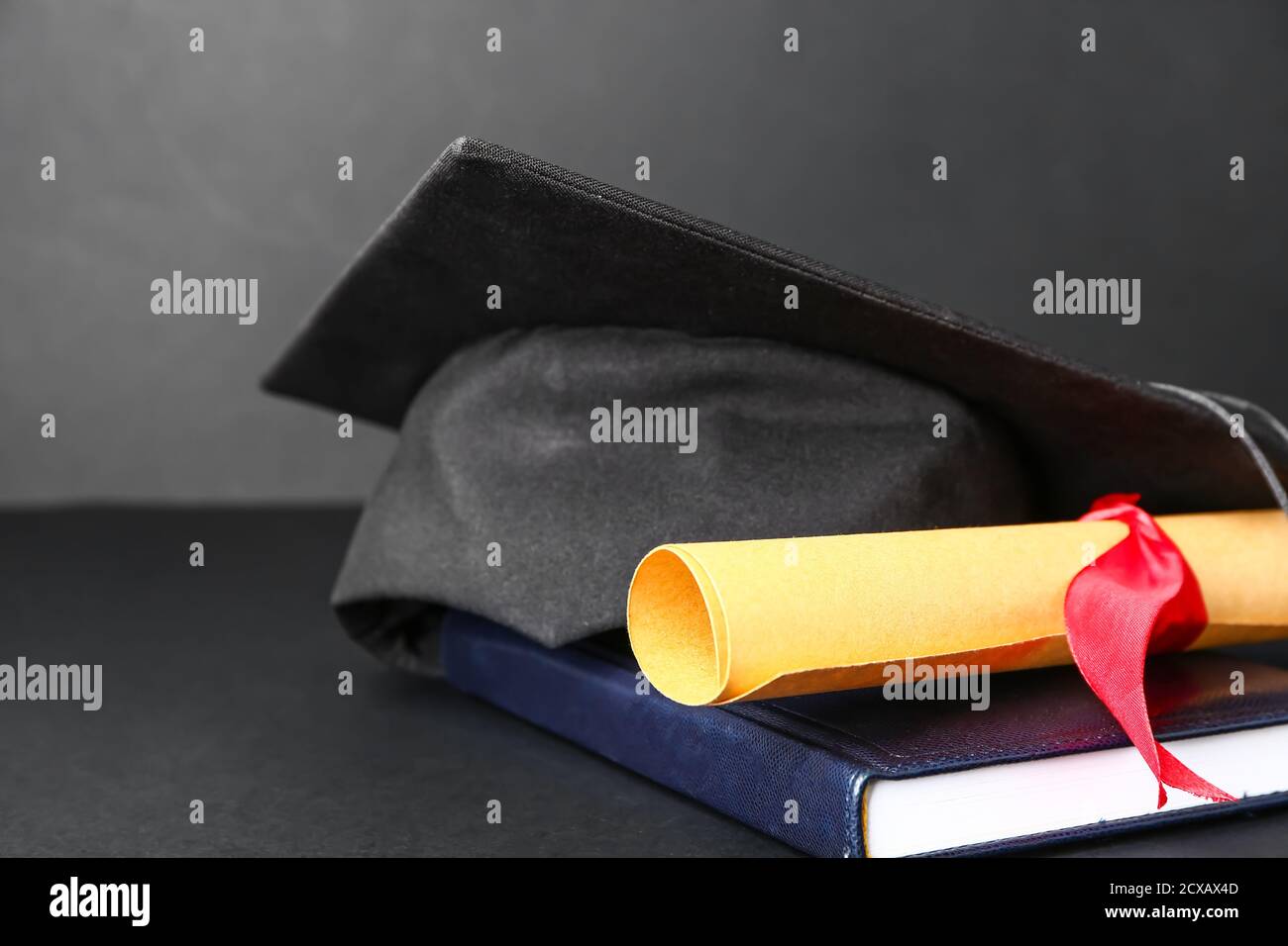 Graduation hat, diploma and book on dark background Stock Photo - Alamy