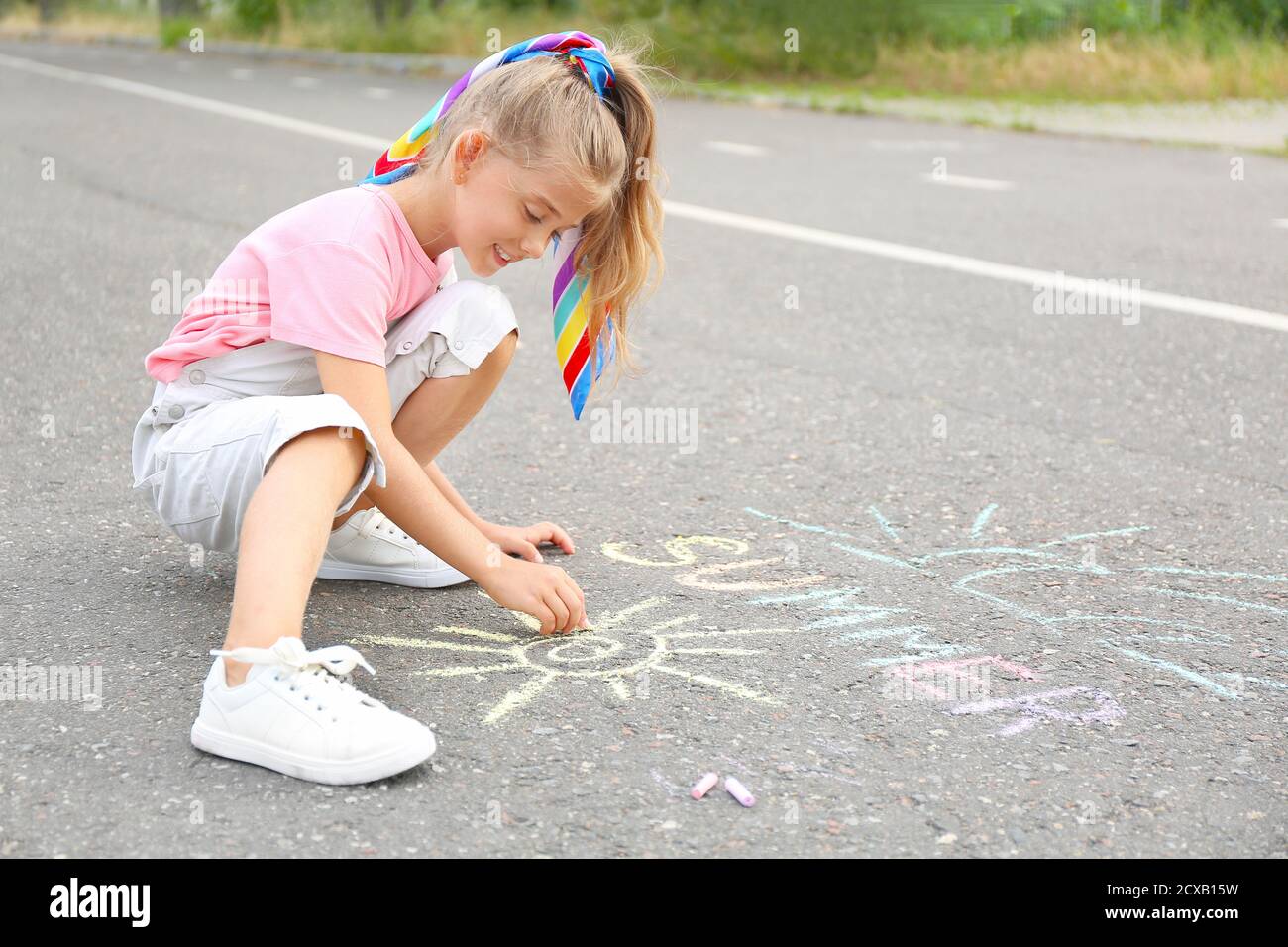 Little girl drawing with chalk on asphalt Stock Photo - Alamy