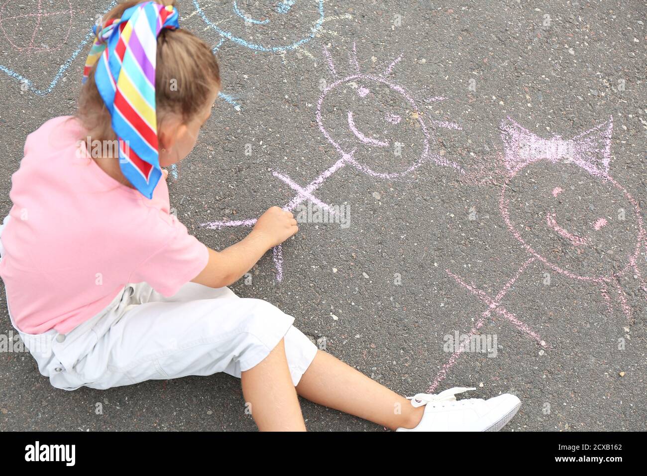 Little girl drawing with chalk on asphalt Stock Photo - Alamy