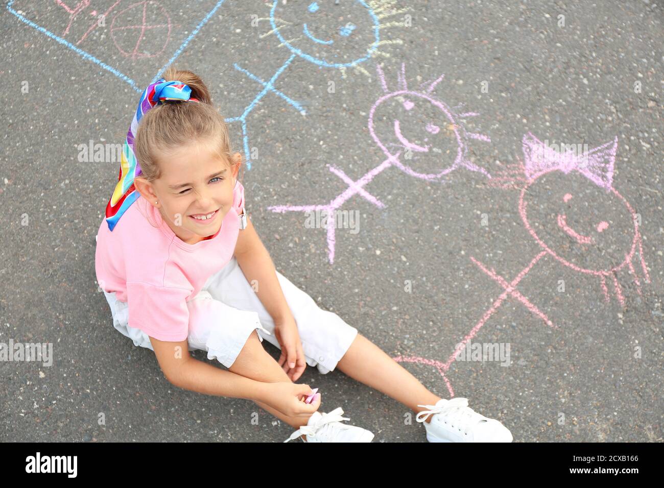 Little girl drawing with chalk on asphalt Stock Photo - Alamy