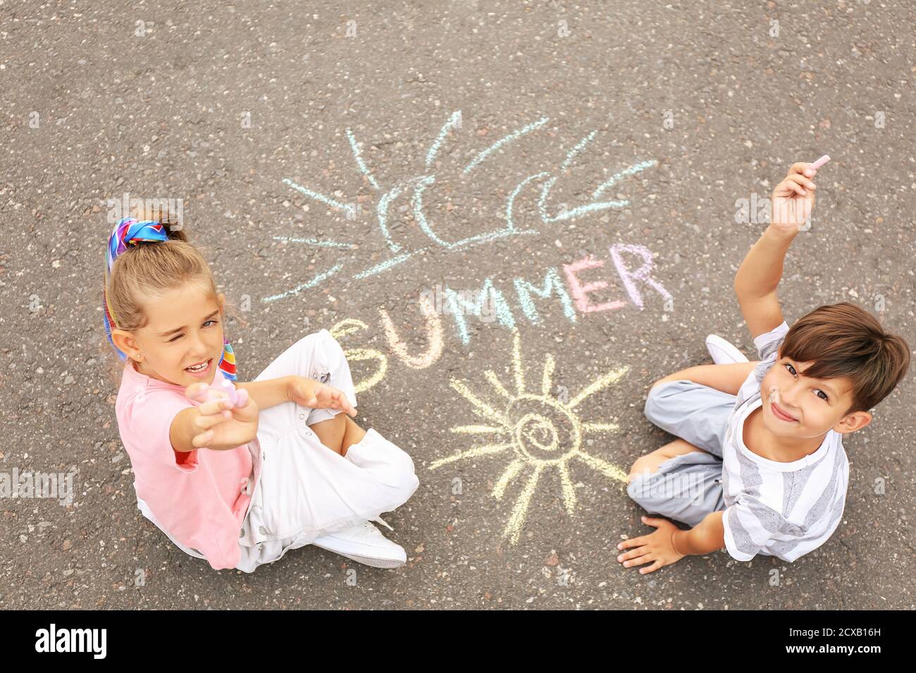 Little children drawing with chalk on asphalt Stock Photo - Alamy